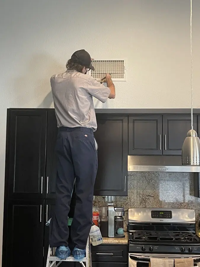 Technician inspecting an air vent during HVAC service in Liberty Lake